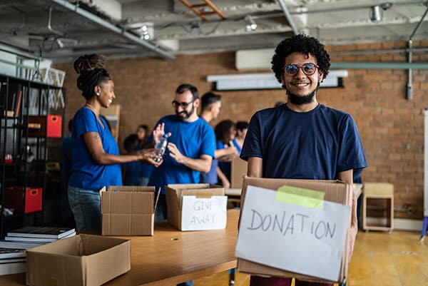 man holding donations sign in front of group of people processing donations