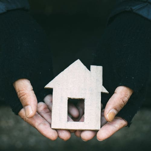 Gloved hands holding cut out of a house