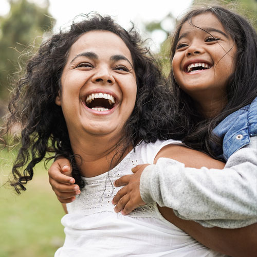 laughing woman with laughing girl on her back